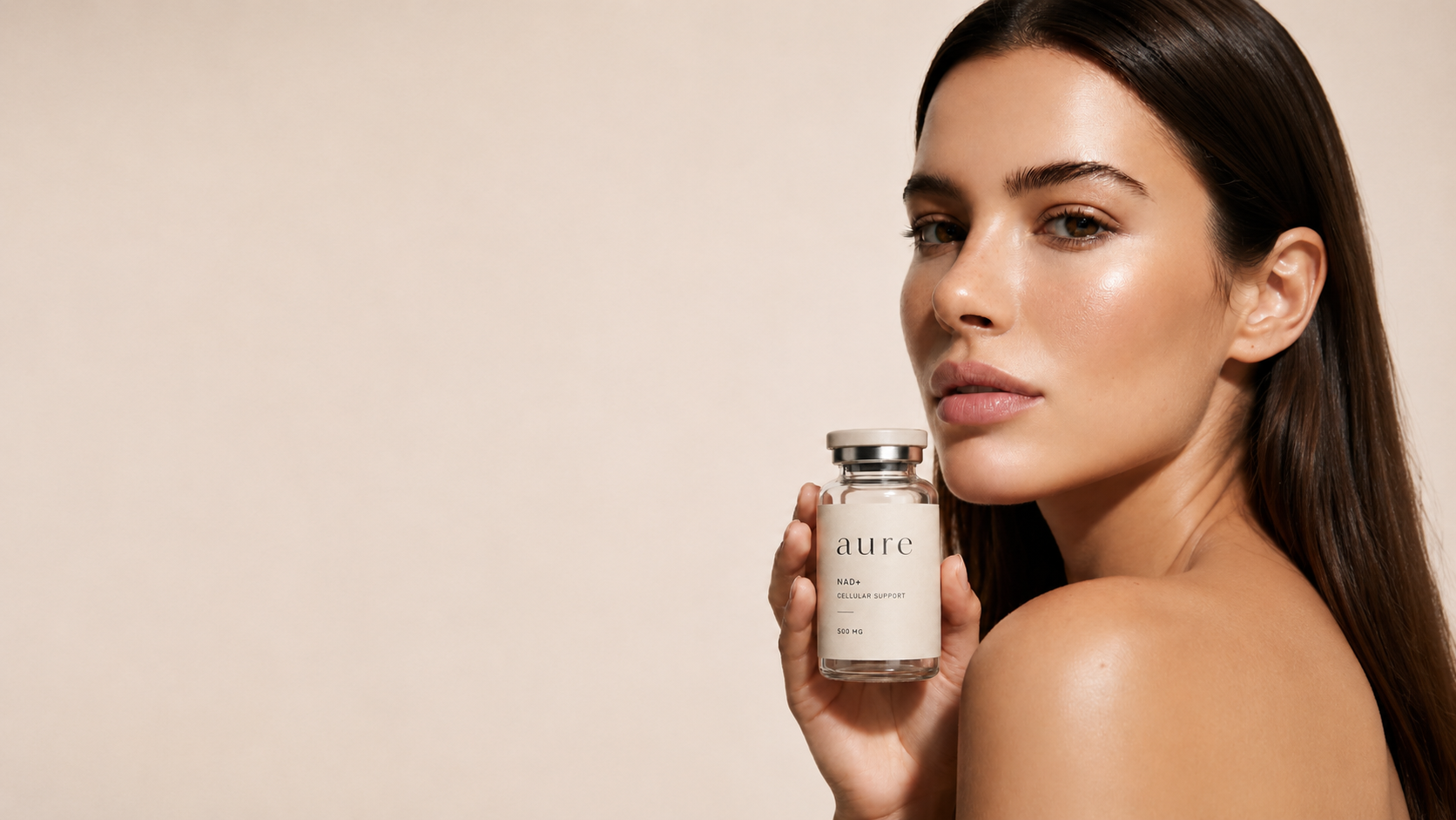Woman holding an Aure NAD+ vial against a warm neutral backdrop